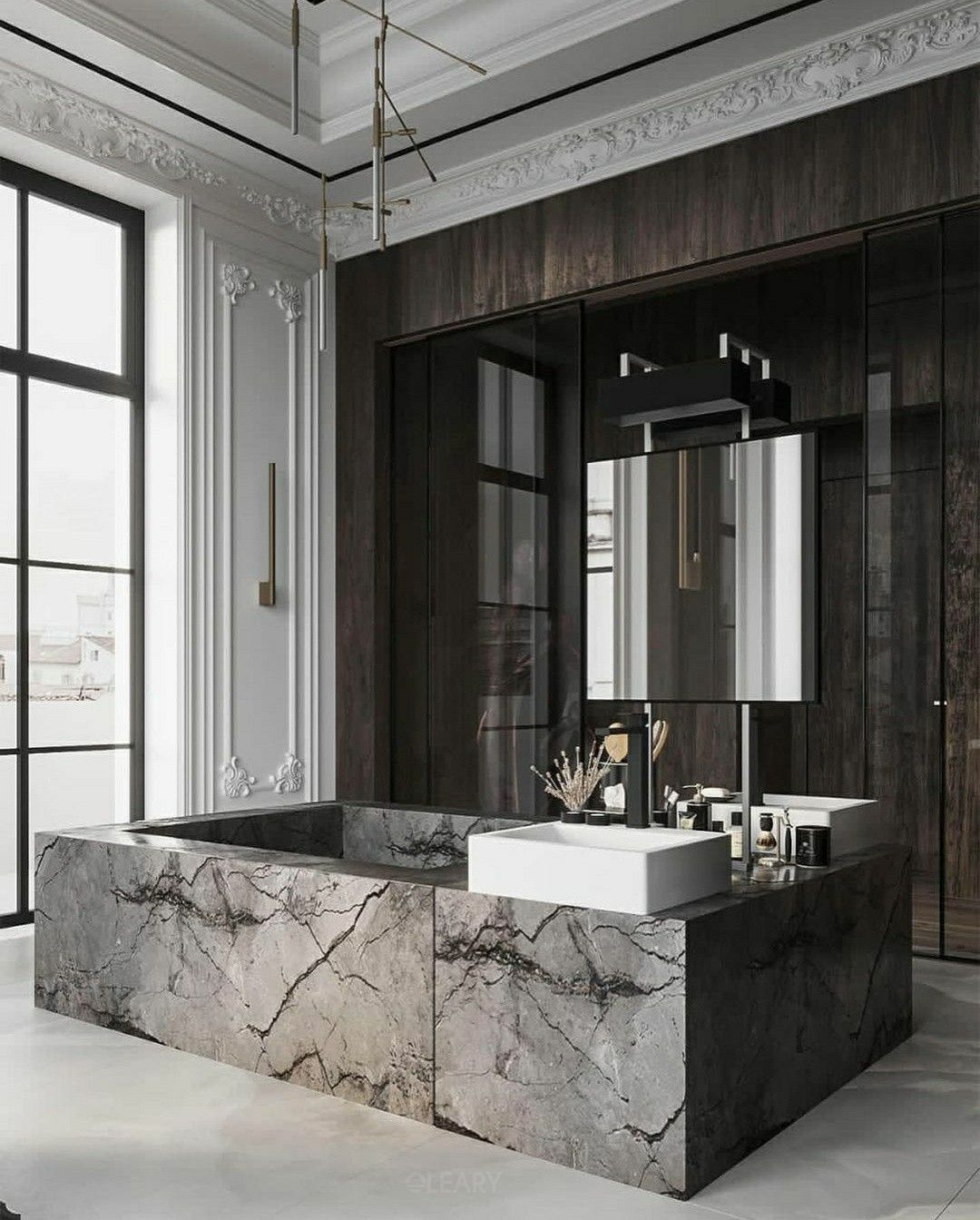 Ultra-luxurious bathroom featuring a monumental, freestanding square marble bathtub and vanity island crafted from dark veined marble, which also hosts a modern white creative vessel washbasin, set within a grand room with classical boiserie walls and contemporary lighting.
