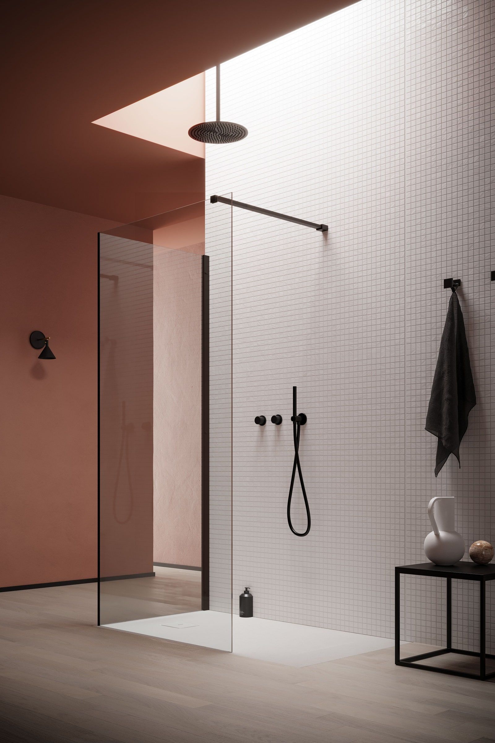 Serene minimalist modern bathroom featuring a walk-in shower with a single frameless glass panel, a matte black ceiling-mounted rain shower head positioned under a rectangular skylight, white square mosaic tiled walls, and a contrasting terracotta-colored accent wall.