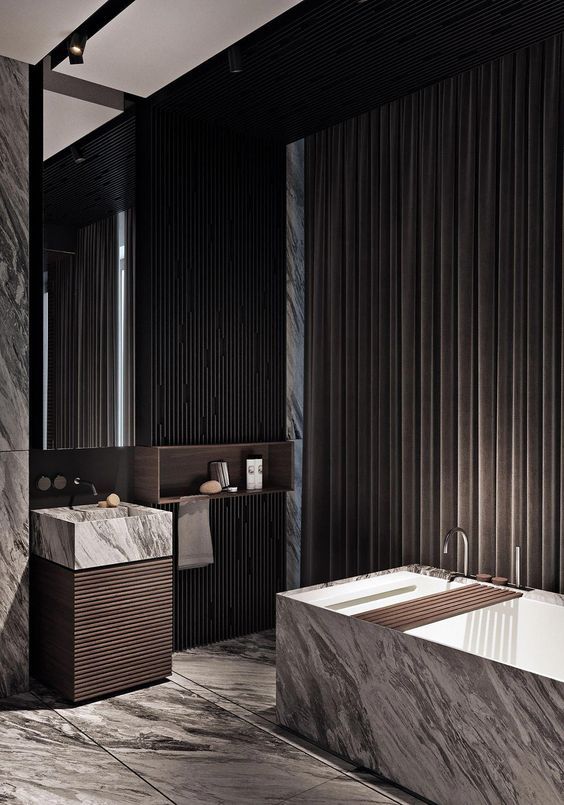  Luxurious modern bathroom featuring a grey marble square freestanding bathtub with a wooden caddy, and a matching marble vessel sink on a dark fluted wood pedestal base, against a backdrop of marble and dark wood paneled walls with heavy curtains.
