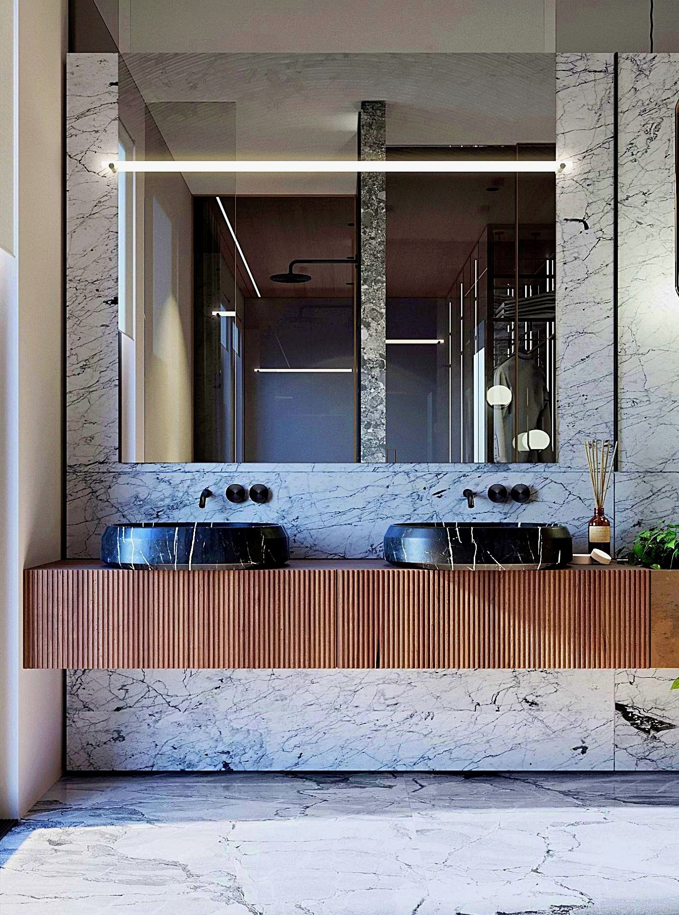 Luxurious master bathroom featuring two dark marble vessel sinks elegantly placed on a fluted wooden wall-hung vanity, against a backdrop of white marble walls.