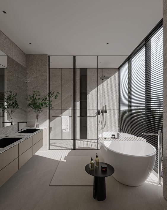 A luxurious modern bathroom featuring a white freestanding oval bathtub near a large window, and a long, light-toned double sink bathroom vanity, showcasing contemporary design and serene ambiance.