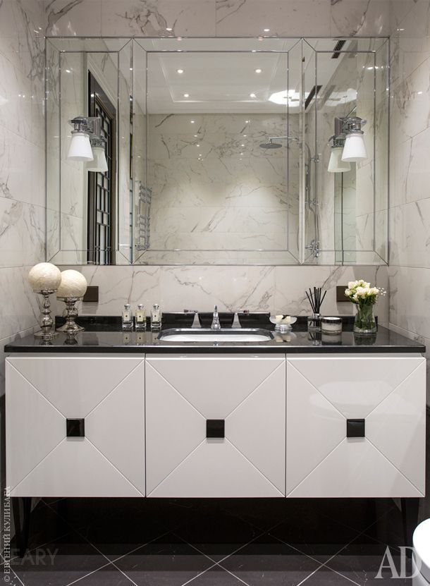 Modern classic bathroom featuring a light-colored vanity with geometric patterns, a black countertop, and a large mirror with beveled edges.
