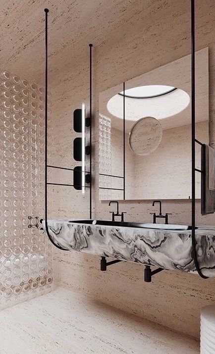 An ultra-modern bathroom with a wall-mounted integrated marble trough sink supported by black ceiling rods, set against travertine walls and a glass block partition.