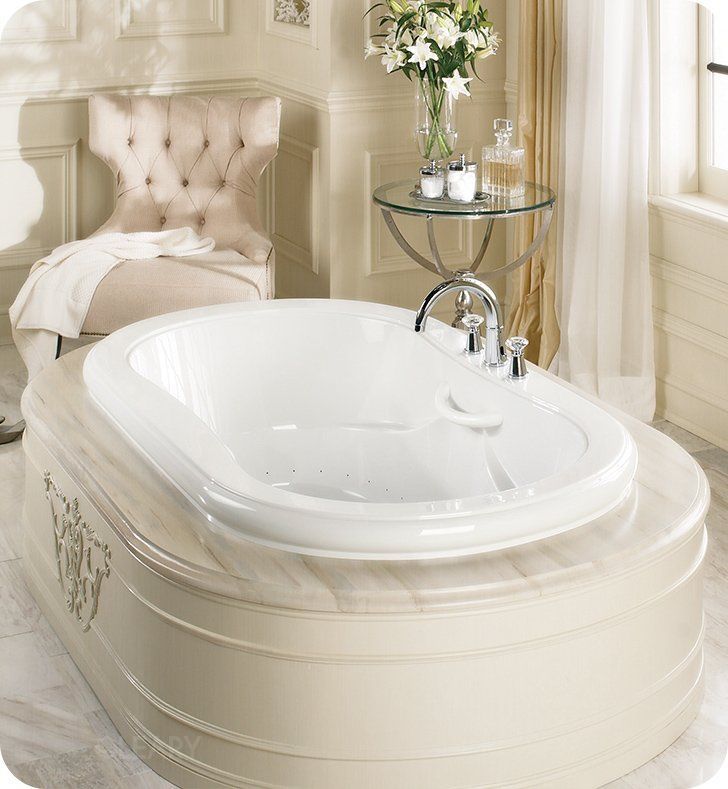 A luxurious classic bathroom featuring a white jetted drop-in bathtub with a cream-colored paneled surround, marble top, and a tufted armchair in the corner.