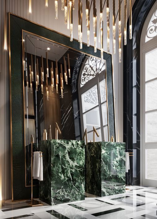 A breathtaking luxury bathroom featuring twin green marble pedestal sinks with gold faucets, a massive floor-to-ceiling statement mirror, and cascading gold lighting, epitomizing opulent interior design.