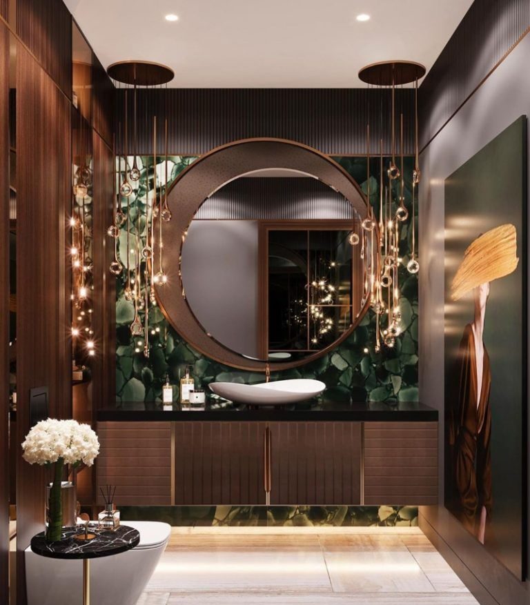 A breathtakingly luxurious bathroom featuring a dark wood floating bathroom vanity with a white vessel sink, set against a backlit green agate wall, a crescent moon mirror, and cascading gold pendant lights.