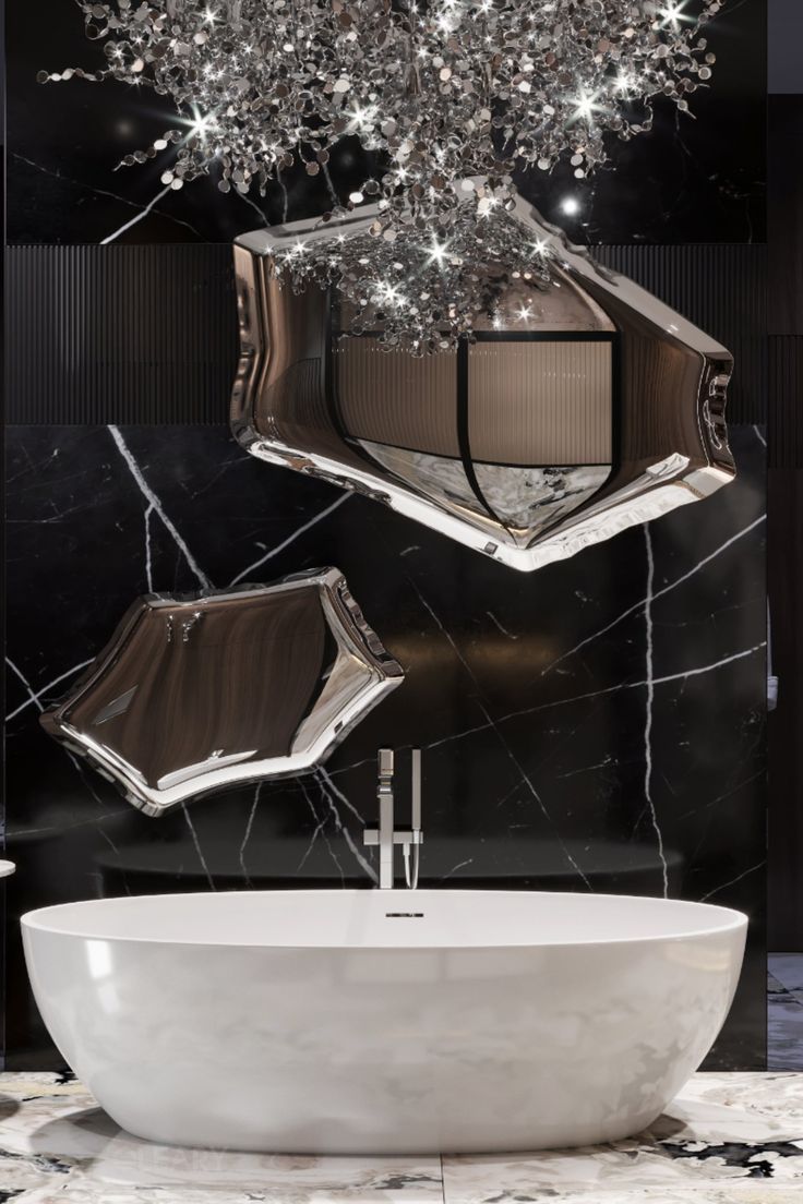A luxurious bathroom featuring a deep white freestanding bathtub set against a dramatic black marble wall with two large, artistic silver-framed statement mirrors and a crystal chandelier.