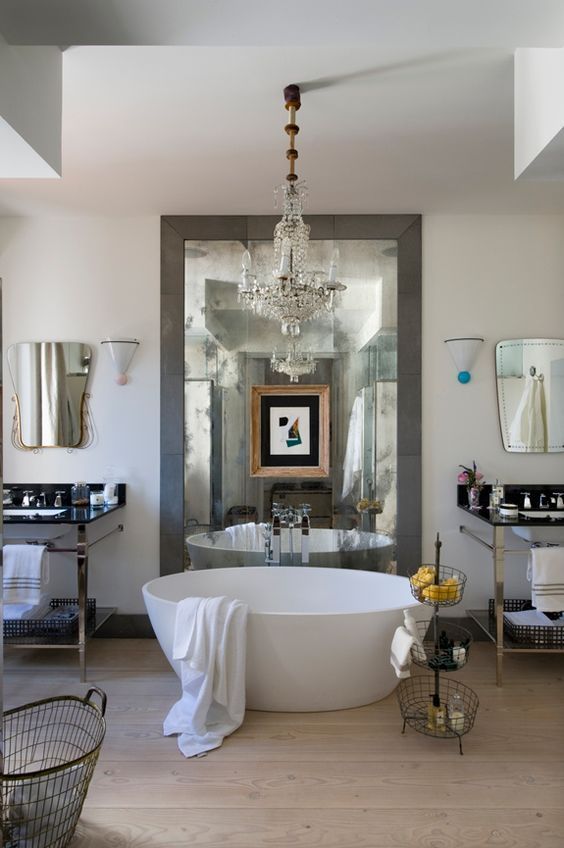 A luxury eclectic bathroom featuring a modern matte white solid surface bathtub placed under a classic crystal chandelier, creating a stunning focal point.