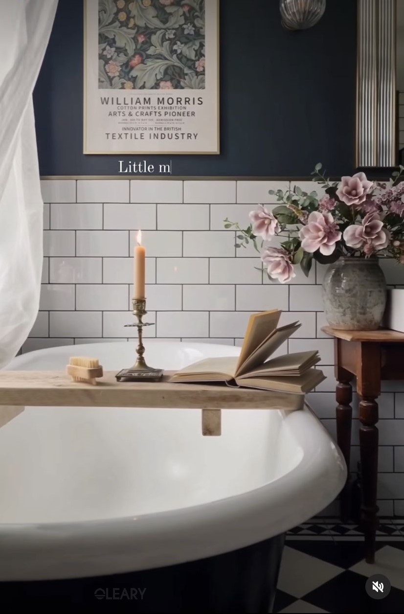 Vintage black bathtub with gold faucet, elegant tiled walls, and floral decorations create a refined bath space.

