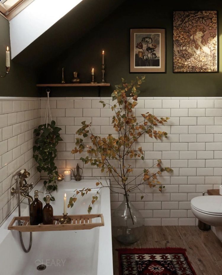Vintage-style bathroom with white brick walls and green accents, decorated with branches and candles for a warm and tranquil atmosphere.

