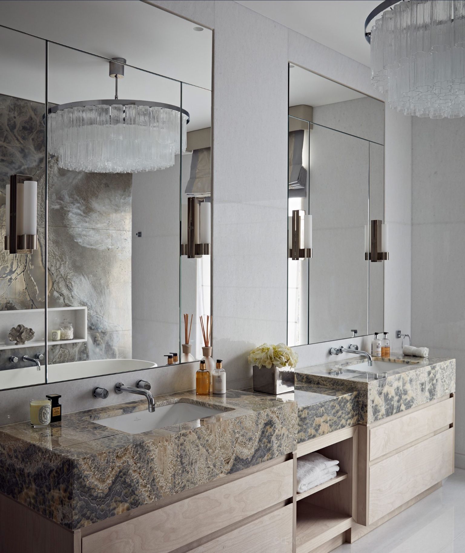 Custom double natural marble vanity with unique veining in a luxurious hotel bathroom, paired with large mirrors and crystal chandeliers.