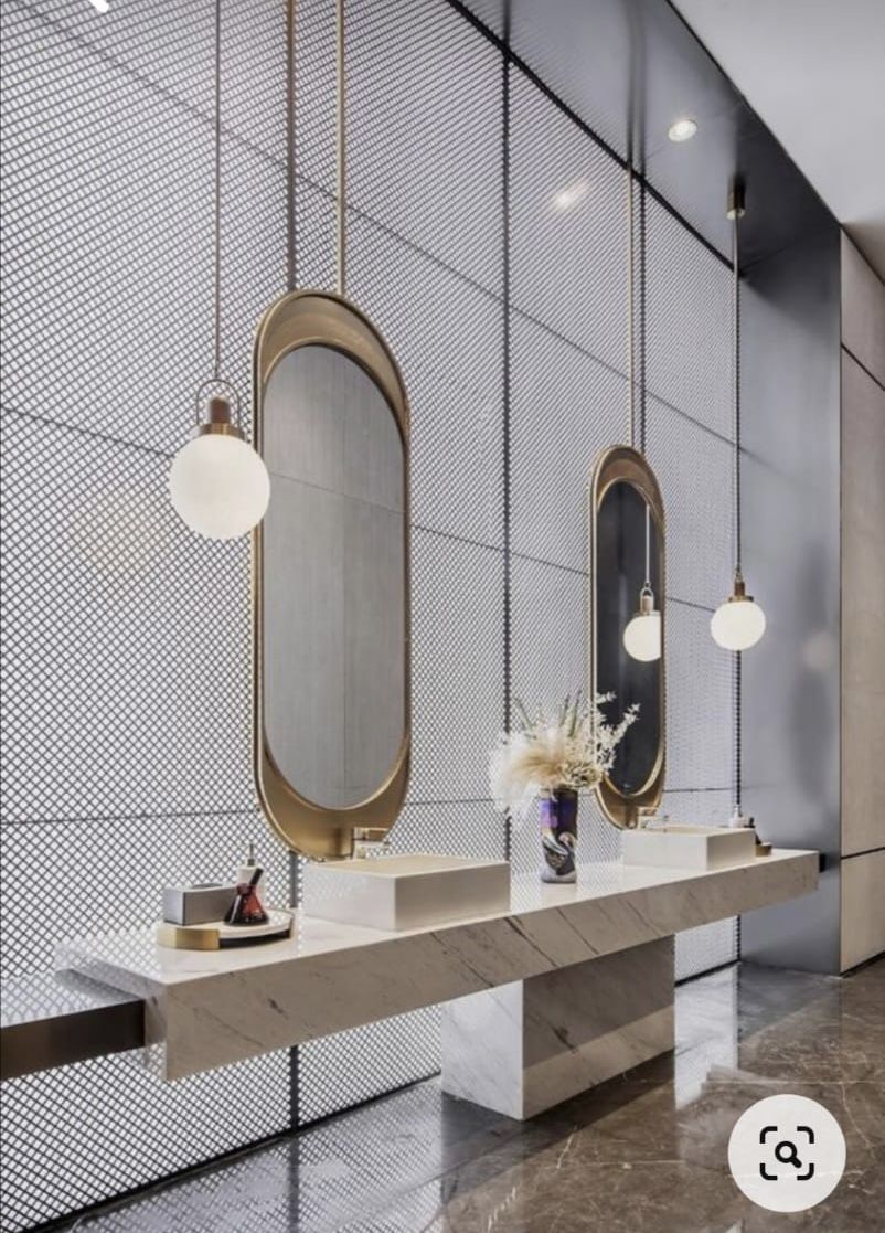 Ultra-modern luxury bathroom featuring a floating white marble vanity with a geometric support, two gold oval suspended mirrors, and a dark mesh-textured accent wall.
