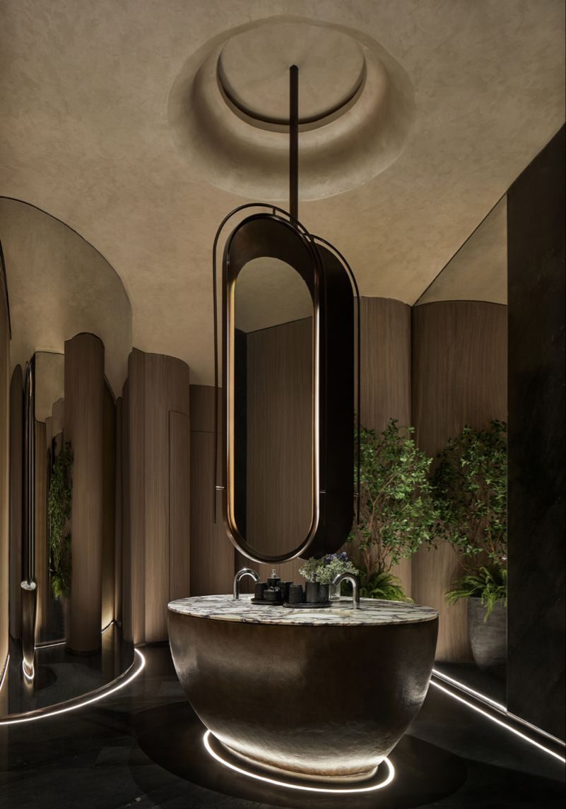 Ultra-luxurious futuristic bathroom featuring a glowing hemispherical freestanding vanity with a white marble top, a large oval suspended mirror with gold accents, and warm curved wooden walls, set on a dark polished floor.