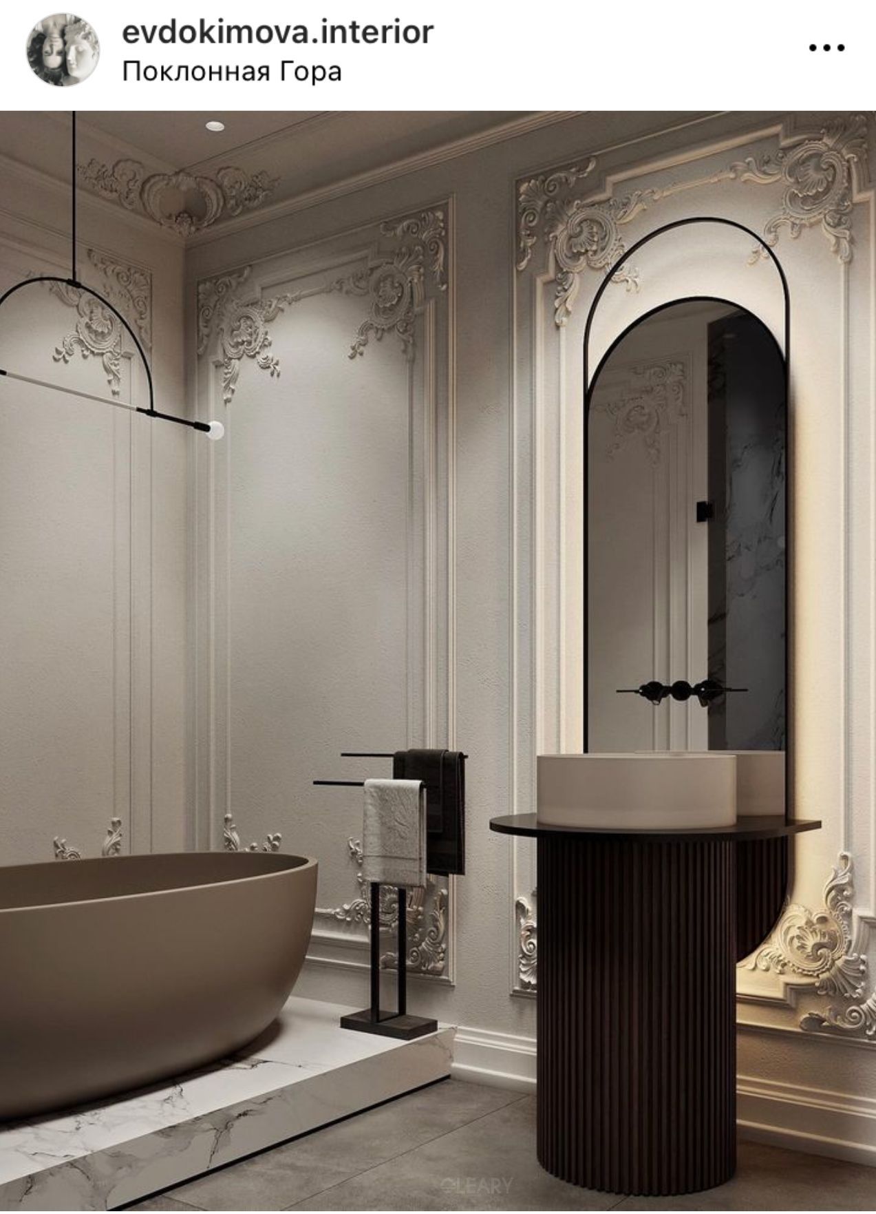 Luxurious bathroom blending classical boiserie walls with modern fixtures, featuring a matte taupe seamless freestanding bathtub and a unique separated pedestal sink with a dark fluted base, light vessel basin, and an arched backlit mirror.