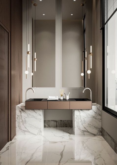 Luxurious modern bathroom featuring a stunning symmetrical double basin bathroom cabinet with a warm metallic finish, dark undermount sinks, supported by white marble pedestals, complemented by tall mirrors, elegant chrome faucets, and sophisticated pendant lighting clusters against dark fluted wood paneling and polished marble floors.