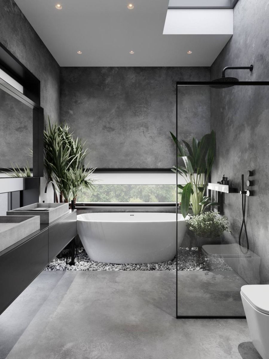 A modern industrial spa bathroom featuring grey concrete walls, a white freestanding soaking tub on river rocks, and a floating concrete vanity with two integrated ramp sinks.