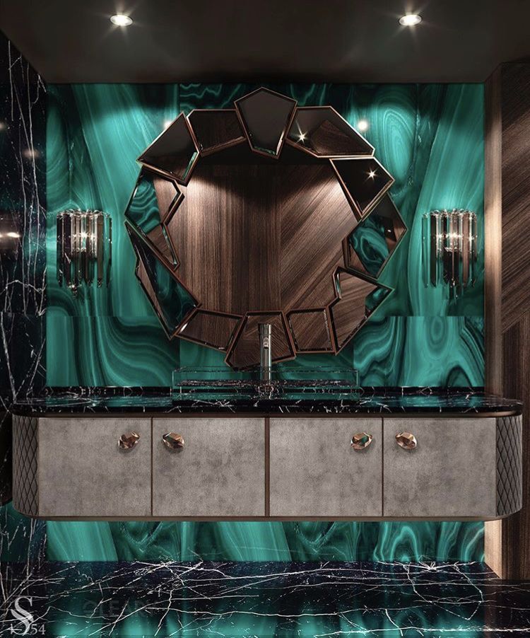 Luxurious master bathroom featuring a green marble accent wall, a unique faceted artistic mirror with wood and metallic accents, and a bespoke grey vanity with dark marble countertop and brass handles.