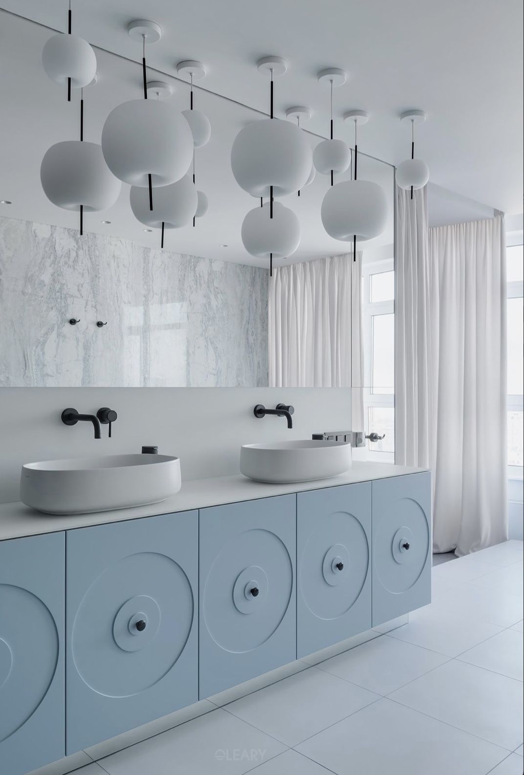 Modern minimalist double bathroom featuring a light blue vanity with concentric circle patterns, white vessel sinks, a large floor-to-ceiling mirror, and multiple white spherical pendant lights.