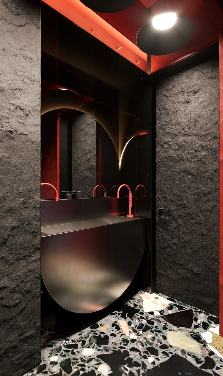 Avant-garde luxury bathroom featuring a dark integrated sculptural metal sink, a vibrant orange-red faucet, rough black stone walls, and hidden orange-red LED accent lighting creating a dramatic atmosphere.