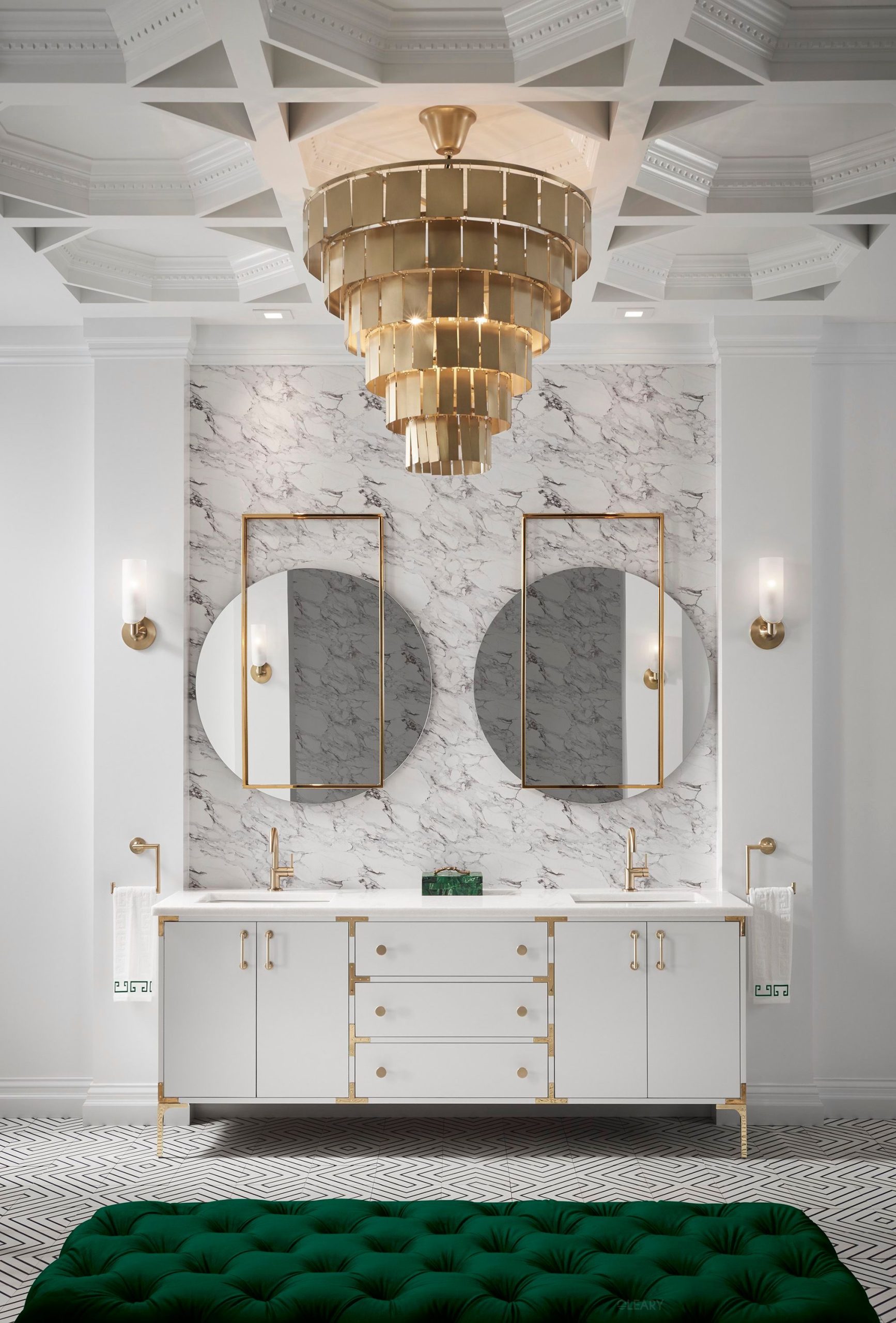 Luxurious Art Deco bathroom featuring a white double vanity with gold accents, two gold-framed rectangular-circular mirrors, a multi-tiered gold chandelier, and white marble walls.