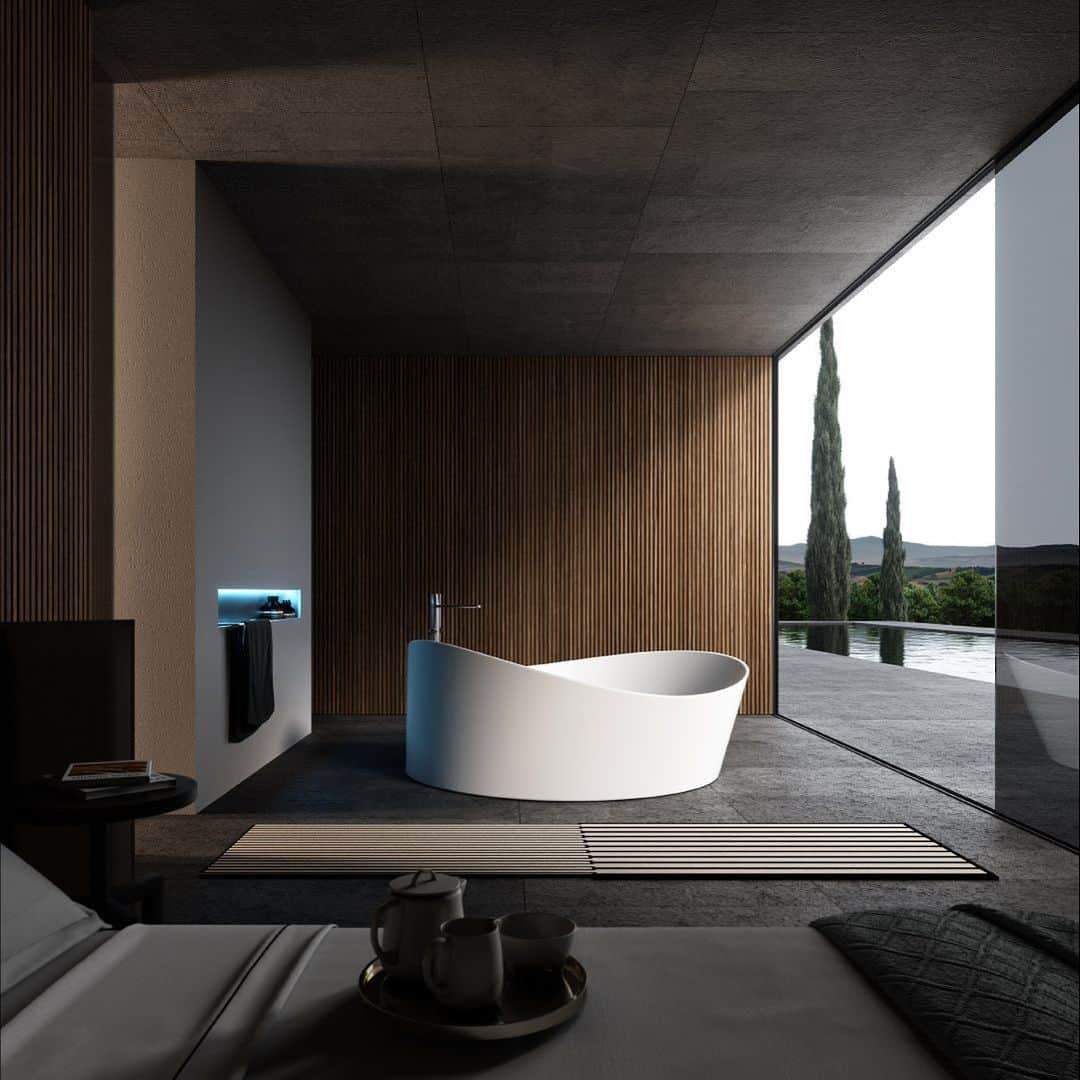 A modern, spacious bathroom features a unique, wave-like white sculptural freestanding bathtub placed in front of a large floor-to-ceiling window overlooking a lush natural landscape. A black minimalist faucet stands nearby, complementing the minimalist design aesthetic.