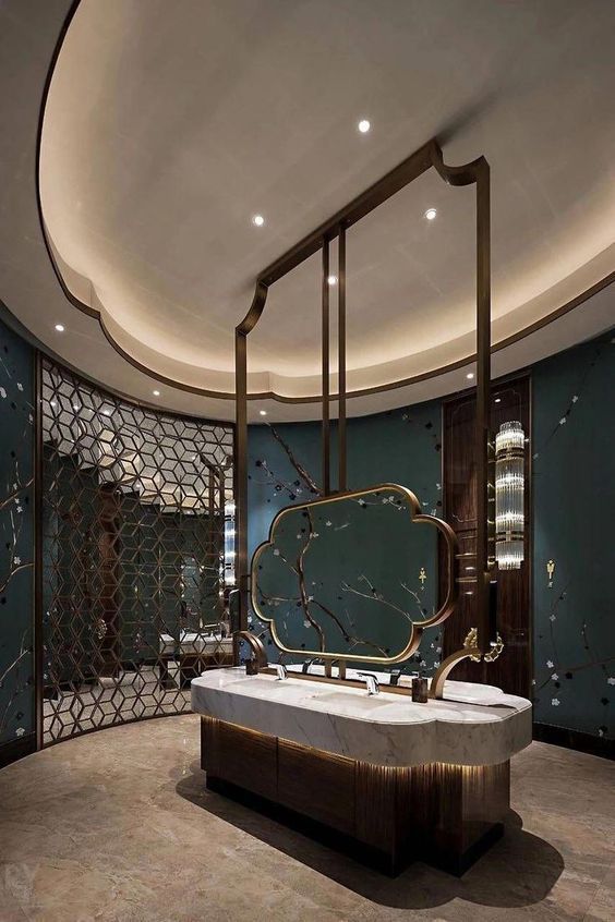 Luxurious bespoke hotel bathroom vanity island with double integrated sinks, a unique artistic mirror, and a dark wood base with underlighting.