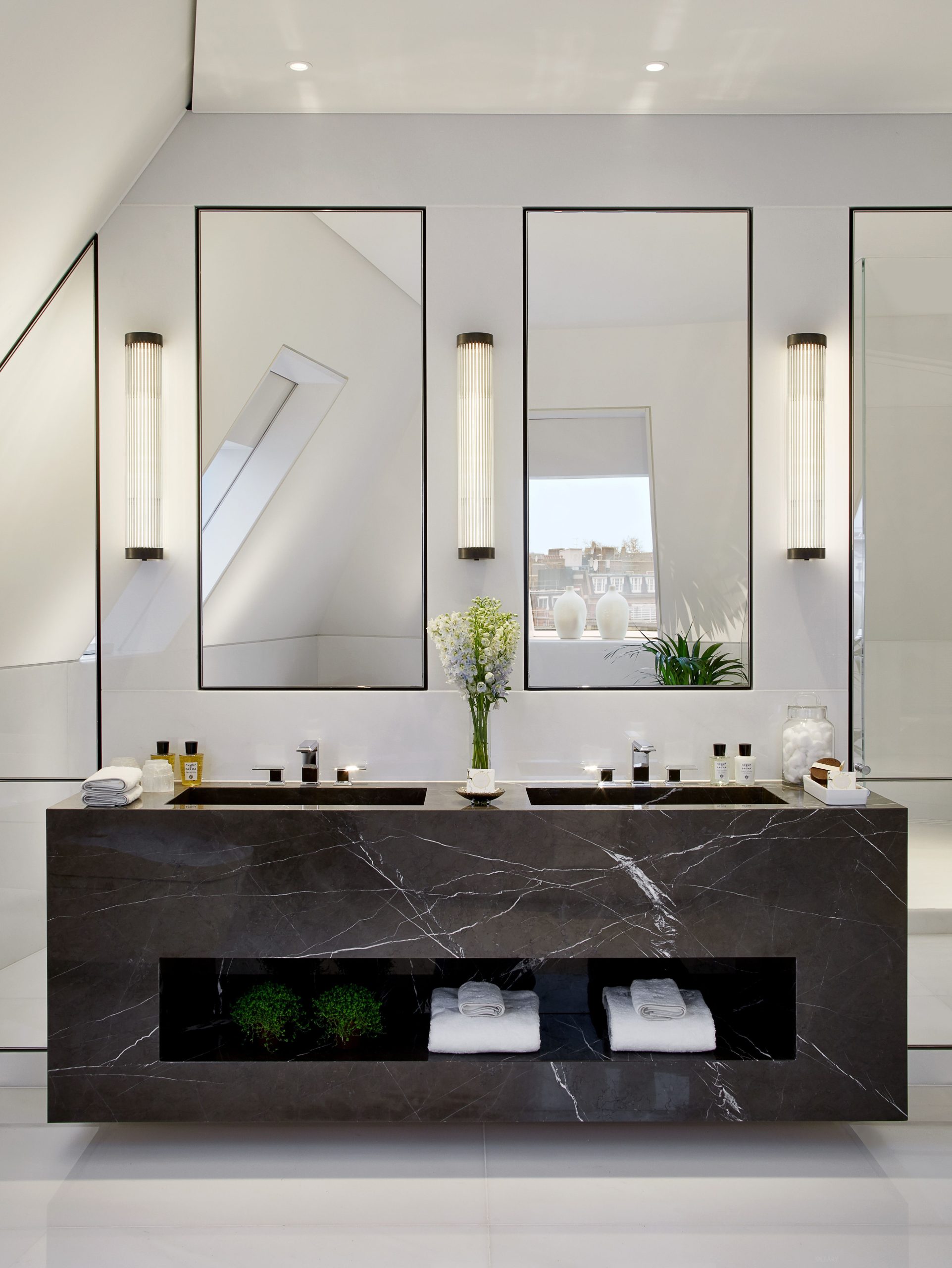 Dark marble double vanity in a modern luxury bathroom with black square undermount sinks and vertical fluted sconces, set against white walls.