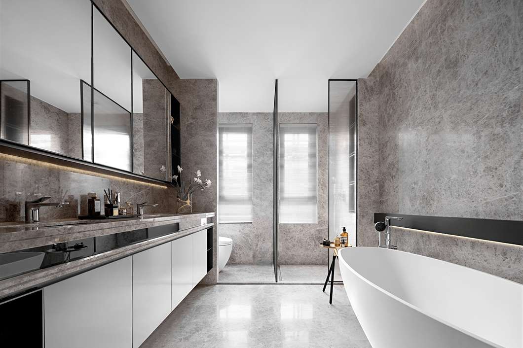 Sleek modern bathroom with extensive grey marble walls and floor, a long floating double vanity, black-framed mirrors, and a glass shower partition.